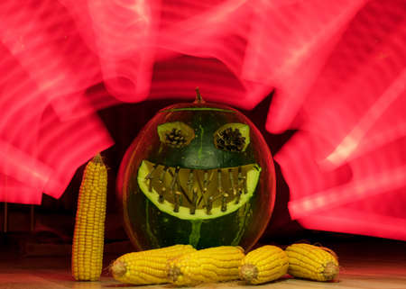 carved green pumpkin on a background of red light paintings, green Halloween Jack o Lanterns, Halloween, autumnの写真素材