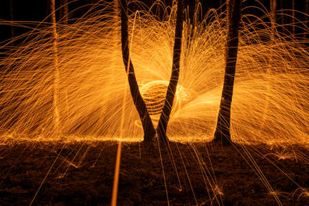 Fire circle spinning from steel wool creating spiral spark, Steel wool spinning fire circle spinning from steel wool creating spiral spark, birch groveの写真素材