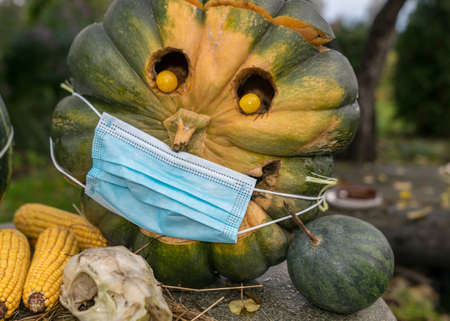 carved decorative pumpkin with face mask, coronavirus (covid-19) time, halloween, autumn timeの写真素材