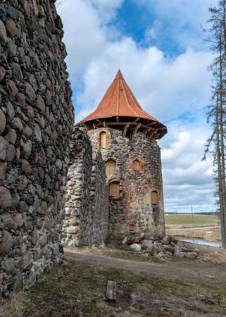 early spring landscape with a view of the castle ruins, the new bright orange roof of the castle tower stands out, Ergeme castle ruins, Valka district, Latviaのeditorial素材
