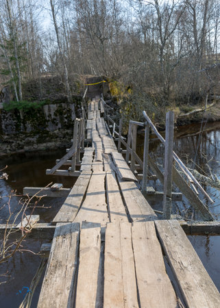 spring landscape with a small wild river, bare trees without leaves, old wooden bridge over the river, spring dayの写真素材