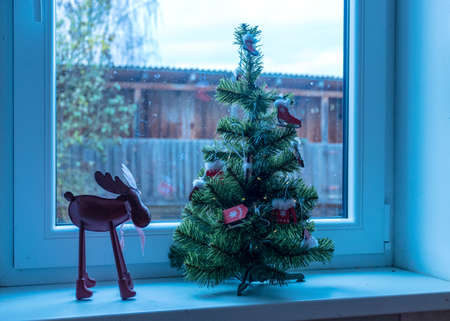 decorated Christmas tree on windowsill, window view, Christmas decor, winterの写真素材