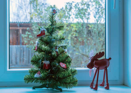decorated Christmas tree on windowsill, window view, Christmas decor, winterの写真素材