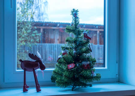 decorated Christmas tree on windowsill, window view, Christmas decor, winterの写真素材