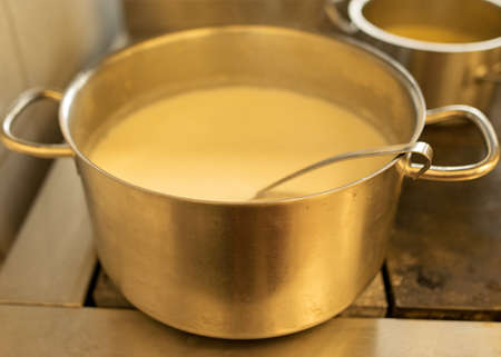 metal pot with cup on stove top with milk soup, school kitchen, eat cooking concept, metal kitchen potの写真素材
