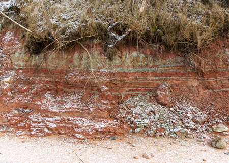 Textured red and white clay outcrop in the sea cliffs. Sandstones and clayey sediments, which provide an opportunity to get to know the structure of the respective rocksの写真素材