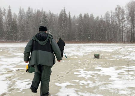 Ice fishing. Fisherman walking on a frozen lake, Fisherman enjoying the day, fishing on the ice, winter dayの写真素材