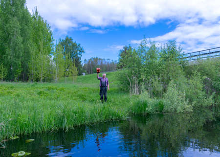 landscape with a man on the river bank, a man houses a greeting, a sunny summer dayの写真素材