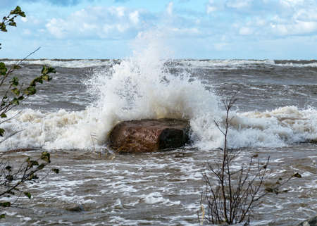 Seascape, sea wave hits stones and explodes, waves and splashes on the shore, dramatic natural background. Vidzeme's rocky seashore, Salacgriva rural area, Latviaの写真素材