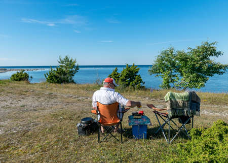 male figure sitting on a chair by the sea, summer vacation, outdoor recreationの写真素材