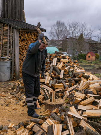 picture of a man cutting wood with logs in the foregroundの写真素材