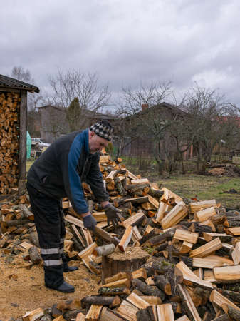 picture of a man cutting wood with logs in the foregroundの写真素材