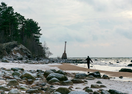 Lighthouse ruins. human silhouette by the sea, Wild beach Baltic coast in December. Vidzeme rocky seashore, Tuja, Kurmrags, Latvia.の写真素材