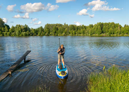 landscape with a woman on a sup board, sunny summer day by the lake, summer timeの写真素材