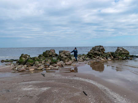 woman silhouette on a rocky sea shore, early spring seascapeの写真素材