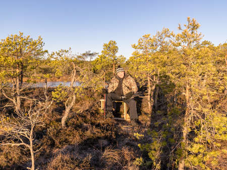 human figure in camouflage costume in swamp, sunny morningの写真素材