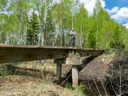 landscape with a man on an old and abandoned reinforced concrete bridge for a train, a bridge over a swamp ditch, a peat train walked over the bridgeの写真素材