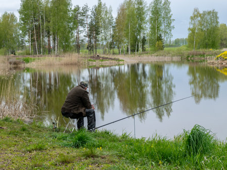 spring landscape with a fisherman on the shore of the lake, fishing accessories in the green hall...