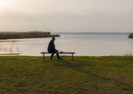 autumn view of the lake, foreground of the lake meadow, human figure on the shore of the lake, Lake Burtnieki, Latviaの写真素材