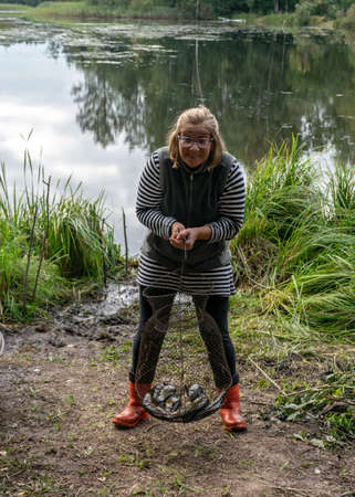 photography with a fisherman who is happy, she shows her fish, the concept of fishing, fishing as a hobby, outdoor recreationの写真素材