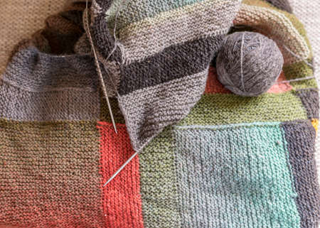 beautiful knitted wool scarf with a ball of wool yarn and wooden knitting needles, knitted background and texture, handmade, knitting pattern backgroundの写真素材