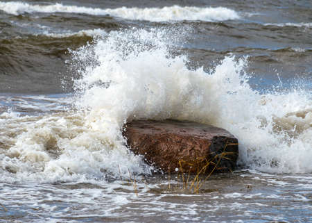 Seascape, sea wave hits stones and explodes, waves and splashes on the shore, dramatic natural background. Vidzeme's rocky seashore, Salacgriva rural area, Latviaの写真素材