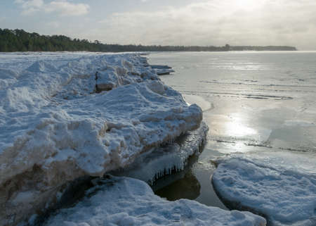winter landscape by the sea, snowy pieces of ice by the sea and ice texture at sea, dunes covered with a layer of white snowの写真素材