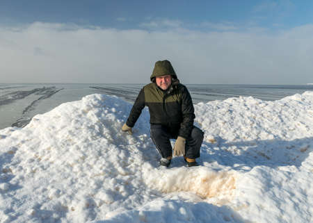 beautiful winter landscape with a man by the sea, white snow covered dunes and ice cubes, sea shore, winter dayの写真素材