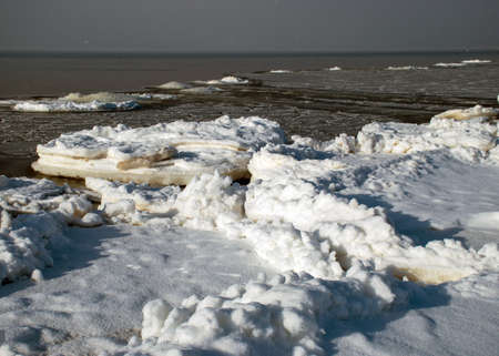 winter landscape by the sea, snowy, interesting ice shapes on the sea shore, dunes covered with a white layer of shining snow, winterの写真素材