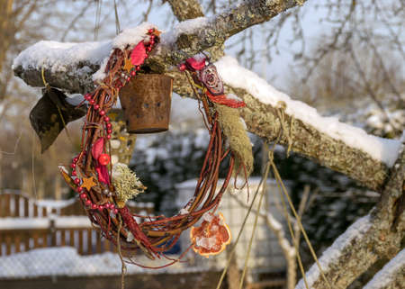 Christmas decorations after the holidays, snow-covered round wicker decorations in the garden, green mesh texture backgroundの写真素材