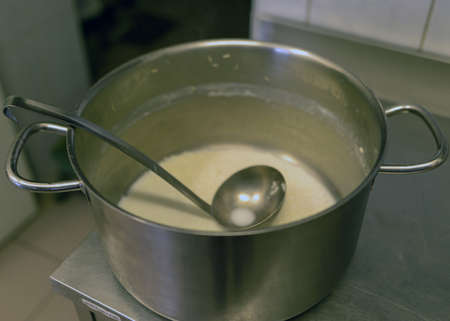 metal pot with cup on stove top with milk soup, school kitchen, eat cooking concept, metal kitchen potの写真素材