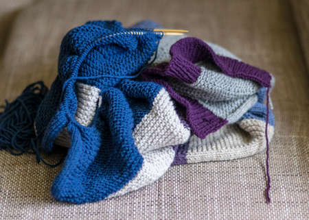 picture with knitted sweater, knitting needles and yarn, close-up view