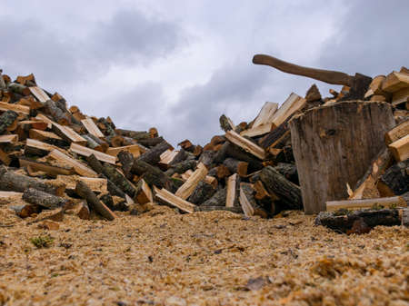 a landscape with a log of wood and an ax in the center, foreground and background of firewoodの写真素材