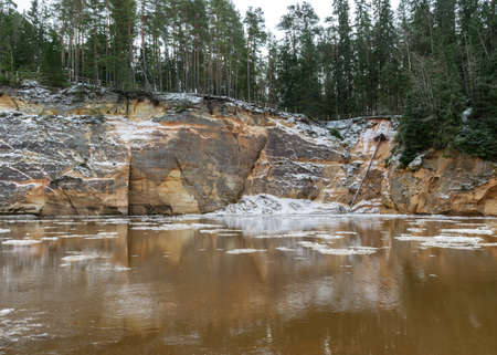 view of the river in early spring, sandstone outcrop, ice cubes in the water, river bank from the opposite bank, Erglu cliffs, river Gauja, Cesis, Latviaの写真素材