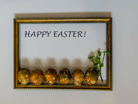 picture with wooden frame and colorful Easter eggs, greeting text "Happy Easter!"の写真素材