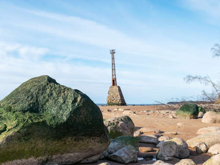 Green stones on the coast in the foreground, Kumrags lighthouse in the background, Vidzeme coast, Baltic Sea, Latviaの写真素材