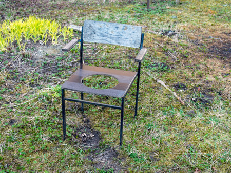 picture with a wooden chair, a hole in the middle of the chair to fit a toilet, an old objectの写真素材