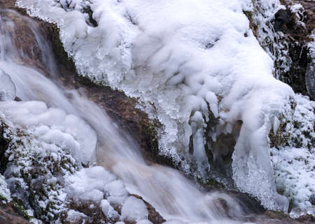 photography with contrasts of frozen and running water, spring water flows over pieces of limestone,...