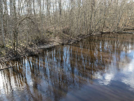 river view from the bridge, small river in early spring, blue sky and reflections in the water,...