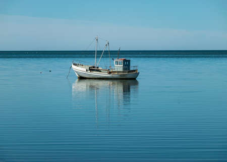 beautiful seascape with a small boat in calm water, sunny summer day, reflections in the water,...