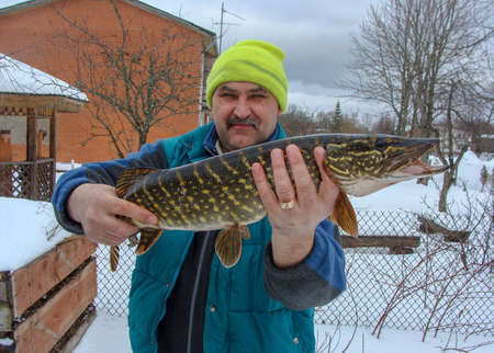 happy fisherman with pike in his hands