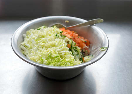 metal bowl with fresh salad of tomatoes, cabbage and cucumbers, eat cooking conceptの写真素材