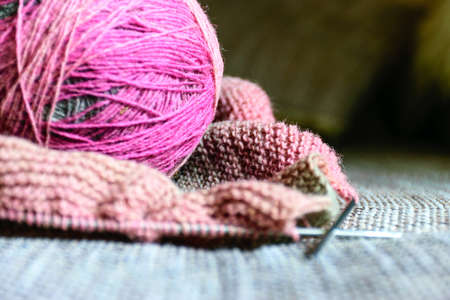 picture with variegated color balls on the knitted textile background, wool yarn and knitting tools - knitting in progressの写真素材