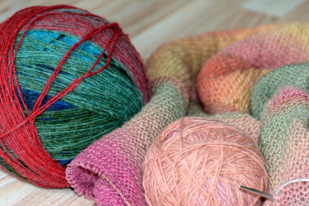 Knitted clothing, accessory in the process of creation. Knitting needles and thread ball, colorful,...