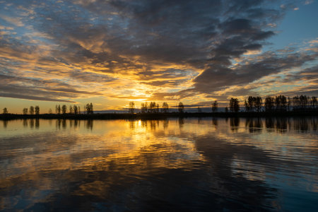 Beautiful lake at sunrise, golden hour sunrise, sunlight and grand cloud reflections on water,...