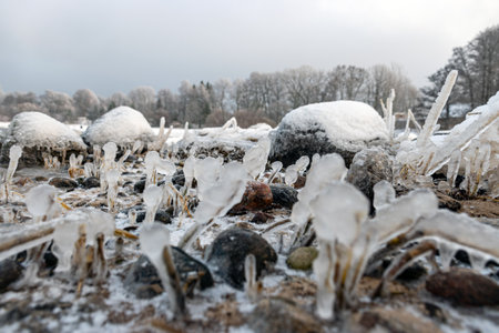 various ice formations on rocks and sandbars on the seashore, ice texture, wind, water and ice working together, winter by the seaの写真素材