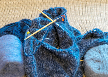 knitted gray-blue sweater, wooden knitting needles and yarn balls, knitting hobby, handmade, hobby