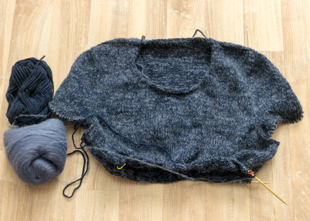 knitted gray-blue sweater, wooden knitting needles and yarn balls, knitting hobby, handmade, hobby