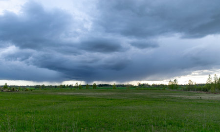 landscape with dark stormy skies on a contrasting green field backgroundの写真素材