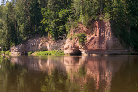 beautiful day on the river, sandstone cliffs and tree reflections in the water, blue sky reflected in the river water, Gauja river, Latviaの写真素材